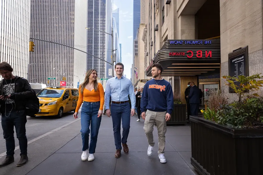 Three people walking down a New York City street together.